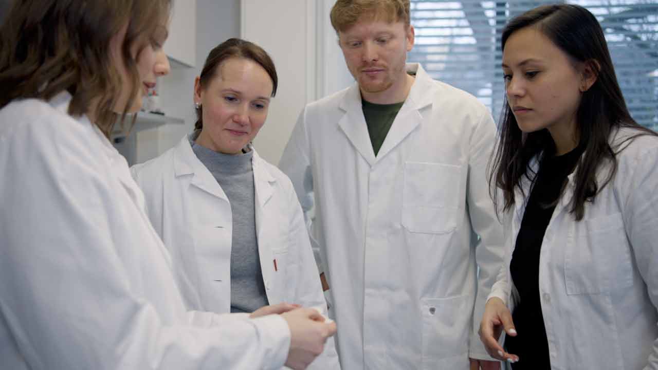 Imagefilm Hannover. Das Team der Phaeosynt GmbH steht im Labor und betrachtet den veganen Schwangerschaftstest „hey mela“. Titelbild des von 52° Film produzierten Videoporträts für hannoverimpuls.