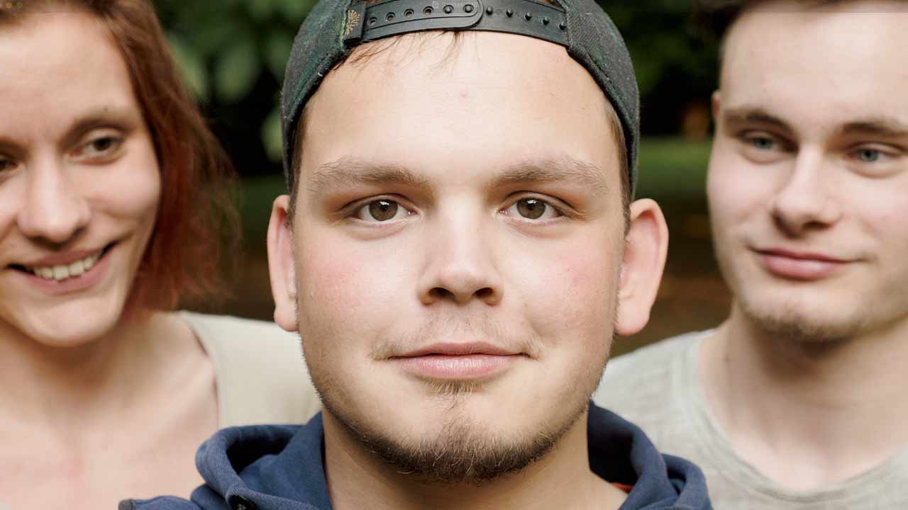Drei Auszubildende vom Wurst-Basar stehen in Nahaufnahme vor der Kamera, eine Person blickt direkt hinein. Titelbild einer Recruitingvideo-Produktion Hannover von 52° Film.