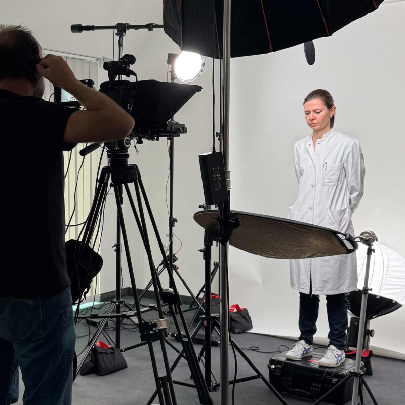 Kameramann und DOP Udo Schloermann von der Videoproduktion 52Gradfilm aus Hannover filmt im extra aufgebauten Studio in der MHH Frau Dr. med. Linda Ferldbrügge. Sie steht auf einem Case und Liest den Text vom Teleprompter.